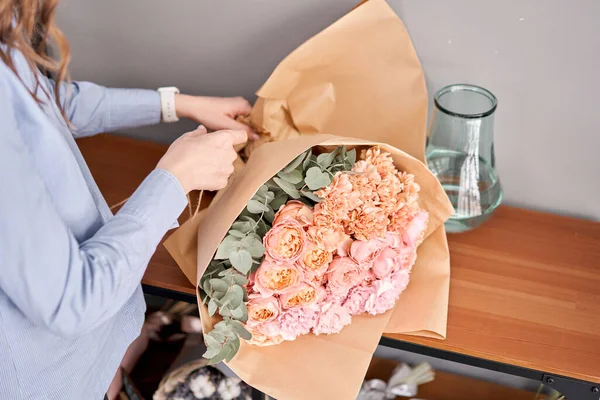Mujer descomprimir conjunto de flores en la mesa de madera. Flores recién cortadas para la decoración del hogar. Entrega flor . — Foto de Stock
