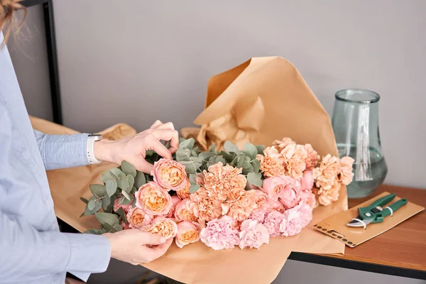 Mulher descompactar flor set na mesa de madeira. Flores frescas cortadas para decoração casa. Flores de entrega . — Fotografia de Stock