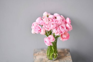 Bahar arkaplanı, çiçek duvar kağıdı. İranlı düğün çiçeği. Açık gri arka planda bir demet pembe ranunculus çiçeği. Eski ahşap masadaki vazo. Duvar Kağıdı