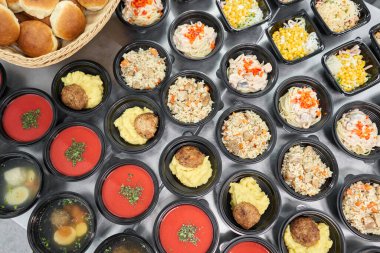 Bir sıra plastik tek kullanımlık beslenme çantası ve sağlıklı doğal yiyecekler. Çorbalar, kremalı çorba, garnitürlü ana yemek, salatalar. Yemek servisi. Ofiste öğle yemeği..