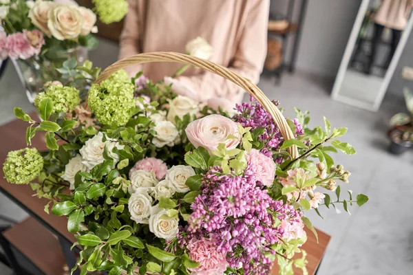 Conceito de loja floral. Mulher florista cria arranjo de flores em uma cesta de vime. Belo buquê de flores mistas. Bonito grupo fresco. Entrega de flores . — Fotografia de Stock