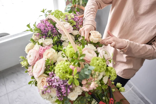 Concepto de tienda floral. Mujer florista crea arreglo floral en una canasta de mimbre. Hermoso ramo de flores mixtas. Hermoso grupo fresco. Entrega de flores . — Foto de Stock