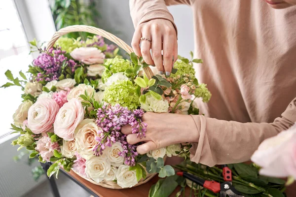 Koncepcja kwiaciarni. Kwiaciarnia kobieta tworzy układ kwiat w wiklinowym koszu. Piękny bukiet mieszanych kwiatów. Ładna banda świeżaków. Dostawa kwiatów. — Zdjęcie stockowe