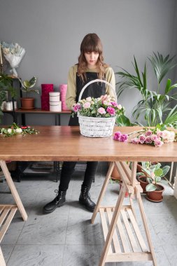 Çiçek dükkanı konsepti. Çiçekçi kadın sepette çiçek aranjmanı yapıyor. Güzel bir buket karışık çiçek. Yakışıklılar. Çiçek teslimatı.