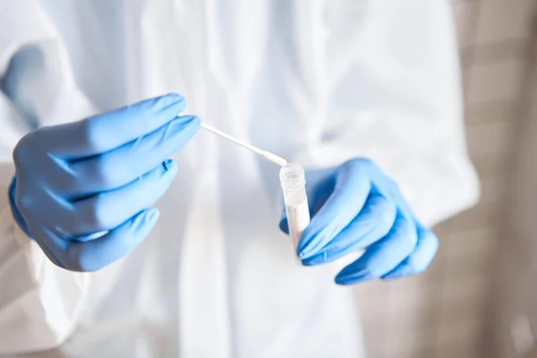 Doctor holding swab test tube for 2019-nCoV analyzing. Coronavirus test. Blue medical gloves and protective face mask for protection against covid-19 virus. Coronavirus and pandemic.