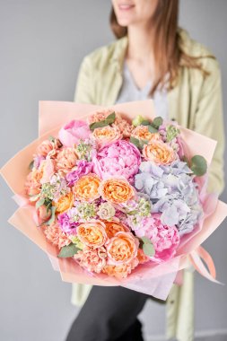 Pembe şakayıklar ve ortancalar. Kadın elinde güzel bir buket karışık çiçek. Çiçek dükkanı konsepti. Güzel, taze bir buket. Çiçek teslimatı.