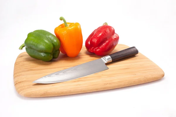 Pimientos frescos en una tabla de cortar madera — Foto de Stock