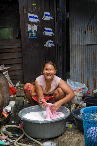 Una mujer que vive en un barrio pobre lava la ropa. —  Fotos de Stock