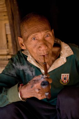 Ahşap pipo ile yaşlı bir adam kendi bambu ev gölgesinde Akha etnik grup fiyatına