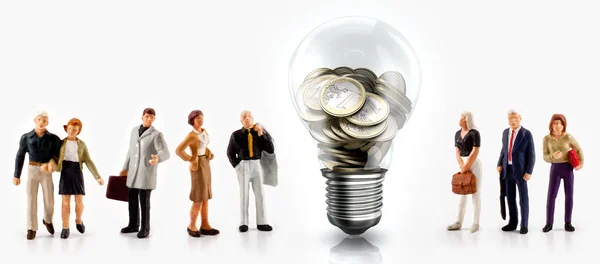 Pessoas em miniatura na frente de uma lâmpada com moedas de euro dentro — Fotografia de Stock