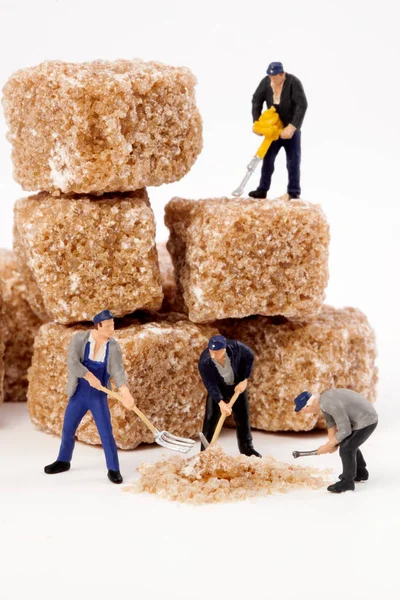 Miniaturmenschen: Arbeiter reduzieren braunen Zucker in Puderzucker. — Stockfoto