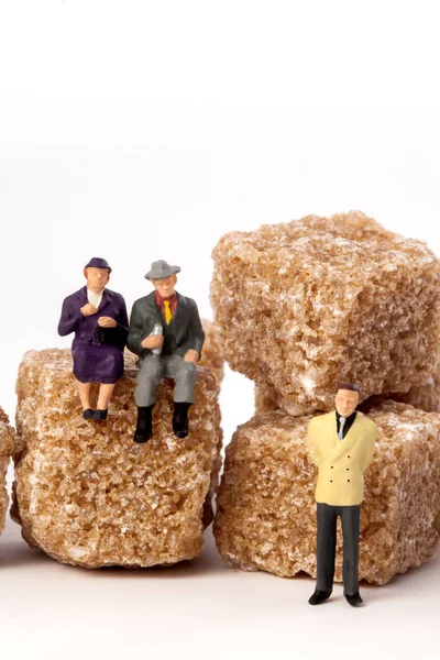 Миниатюрные люди: пожилые, спереди, кубики коричневого сахара . — стоковое фото