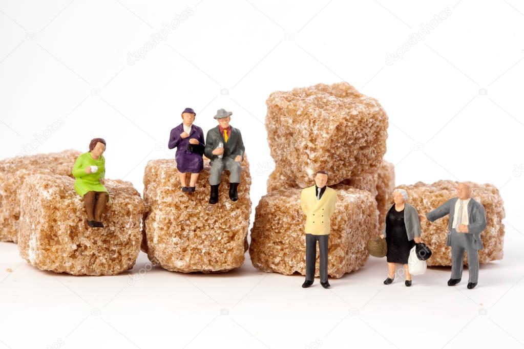 Miniature people: seniors, in front, cubes of brown sugar.