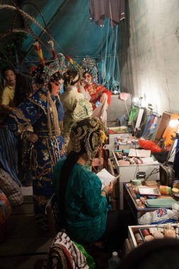 In the backstage of a Chinese opera, actors finish dressing and  clipart