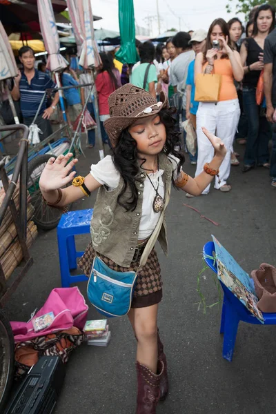 Genç bir kız şarkı söylüyor ve Chatuchak pazarı sokakta dans ediyor 