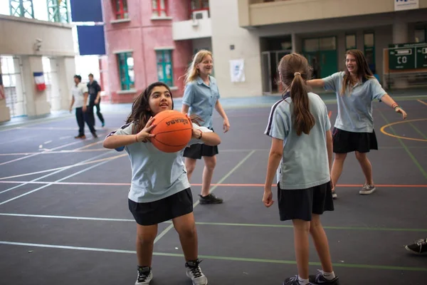 Estudiantes con uniforme divirtiéndose jugando baloncesto . — Foto de Stock