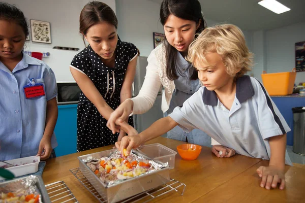 Jóvenes estudiantes toman un curso introductorio en la cocina con su profesor . — Foto de Stock