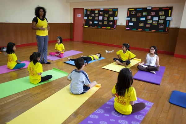 Kleine Kinder nehmen mit ihrer Lehrerin an einer Yoga-Stunde teil. — Stockfoto