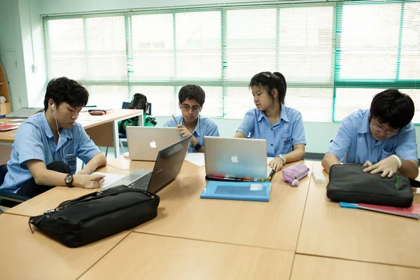 Un grupo de jóvenes estudiantes hacen su tarea en un aula . — Foto de Stock