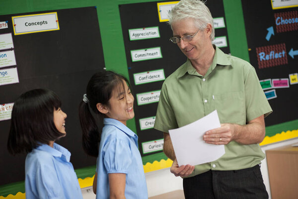 В колледже в Бангкоке школьный учитель исправляет и помогает ученику в его работе.
.