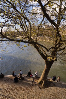 Gençler Bahar, Paris'te Seine kıyısında oturan sıcaklığını tadını çıkarın.