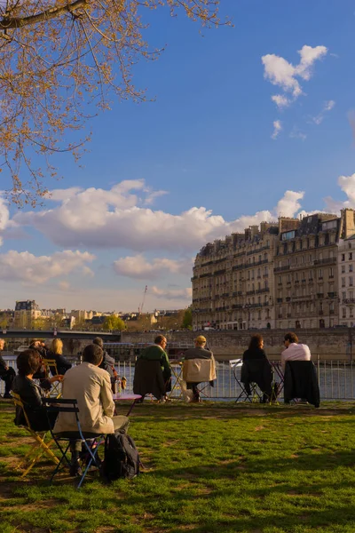 Os turistas bebem e fazem piquenique nas margens do rio Sena, em Paris, durante um dia ensolarado de primavera. — Fotografia de Stock