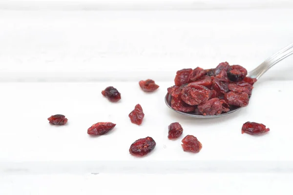 Dried cranberries in a spoon on white wood background — Stock Photo, Image