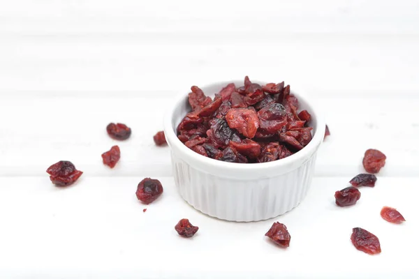 Dried cranberries in a bowl on white wooden background — Stock Photo, Image