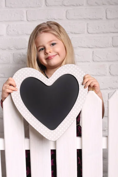 Niño sosteniendo el corazón detrás de la valla. De cerca. Fondo blanco —  Fotos de Stock