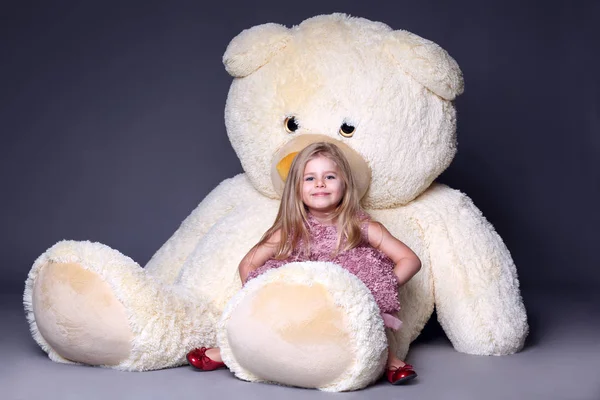 Büyük teddys ayak üstünde oturan küçük kız