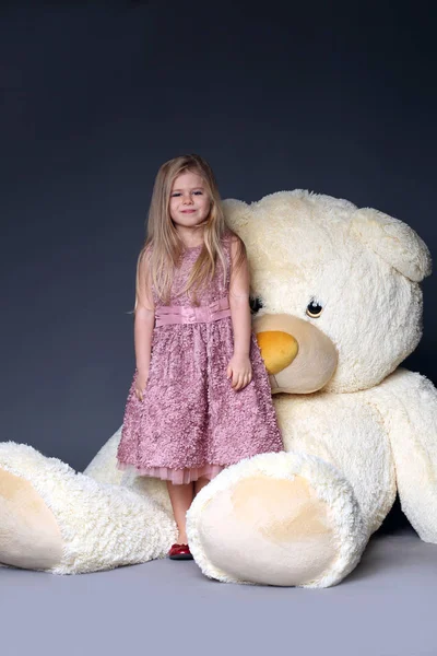 Дівчина стоїть біля величезного плюшевого ведмедя — стокове фото