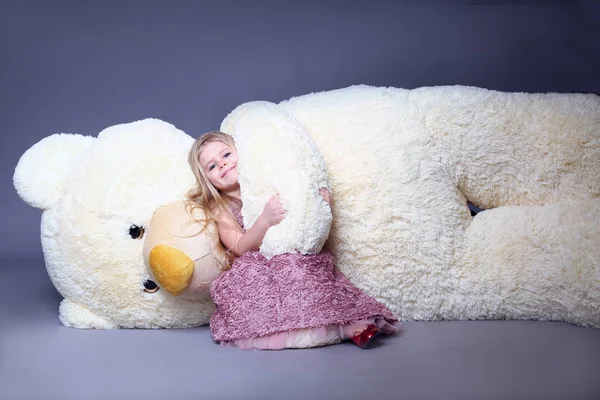 Girl hugging big teddys bear arm