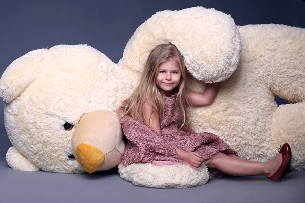 Fille en robe lilas assis sur le grand ours en peluche blanc — Photo