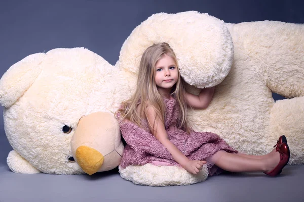 Petite dame en robe lilas posée sur le grand ours en peluche — Photo