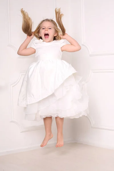 Chica gritando saltando y sosteniendo su cabello. Fondo blanco —  Fotos de Stock