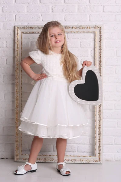 Kind in jurk met hart en frame. Close-up. Witte achtergrond — Stockfoto