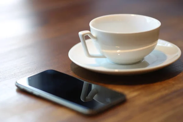 Empty cup and mobile phone. Close up — Stock Photo, Image