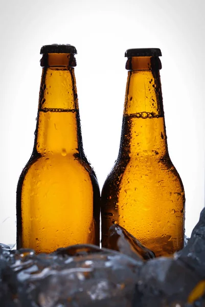 Två flaskor öl i isbitar. Närbild. Vit bakgrund — Stockfoto