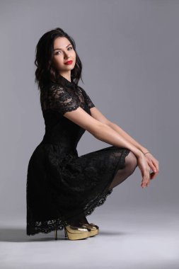 Bayan çömelme topuklar üzerinde. Gri arka plan. Photographie retouchee