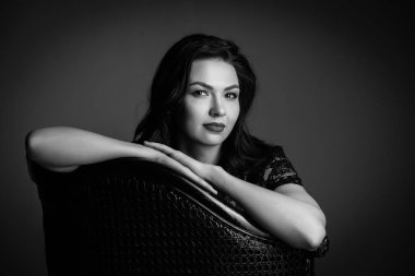 Siyah beyaz sandalye üzerinde oturan bir bayan. Yakın çekim. Photographie retouchee
