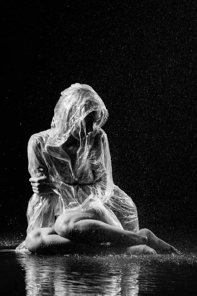 Γυναίκα σε αδιάβροχο κάθεται στο πάτωμα στη βροχή. Μαύρο και άσπρο. Έκθεσης Recorded Memories – retouchee — Φωτογραφία Αρχείου