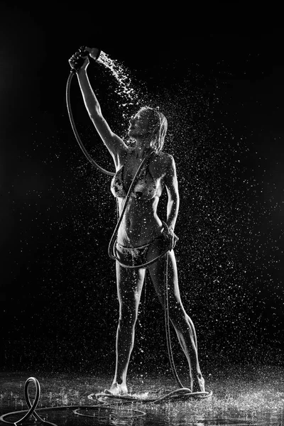 Modell mit schönem Körper unter der Dusche. schwarzer Hintergrund. Fotoretuschee — Stockfoto