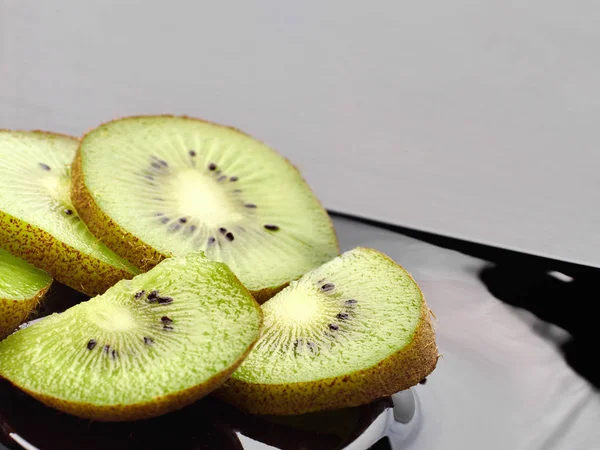 Belos pedaços de fatias de kiwi em um prato escuro . — Fotografia de Stock