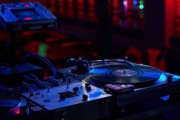 Closeup of a remote DJ with vinyl discs in a nightclub with a be