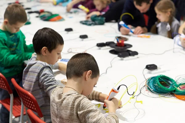 Un grupo de niños aprende a dibujar una pluma 3D con la ayuda de par — Foto de Stock