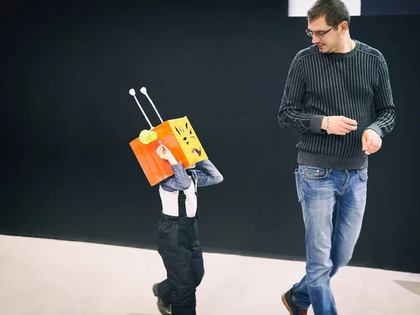 Padre juega con su hijo en traje de robot . — Foto de Stock