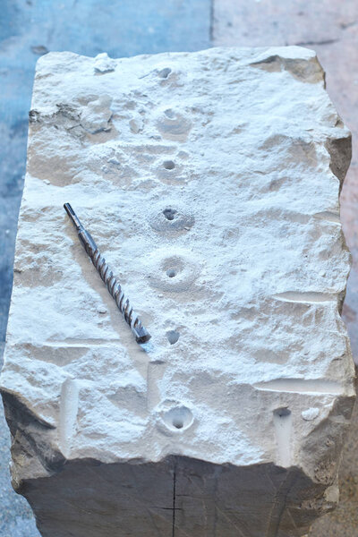 A piece of marble with a drill drilled in many places.
