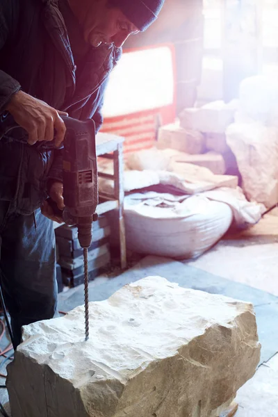 Escultor de trabajo taladra agujeros profundos en el bloque de mármol . — Foto de Stock