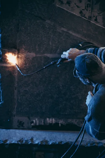 Zaměstnanec s plynovým hořákem zpracovává žula s otevřeným plamenem — Stock fotografie