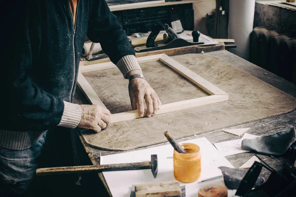 An elderly desk is working in his workshop on the table, making — Stock Photo, Image